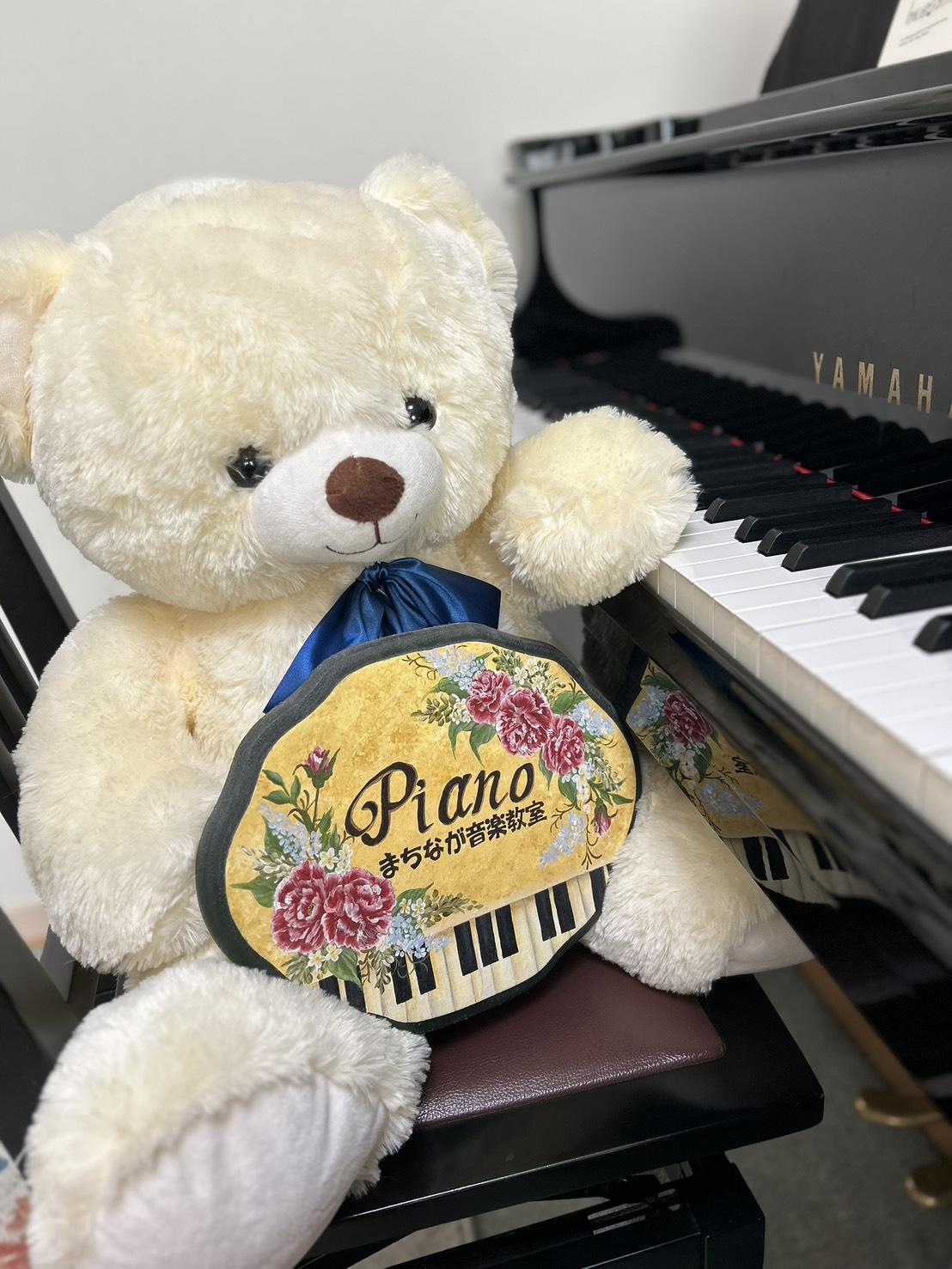ピアノのそばに座る町永音楽教室のくまのぬいぐるみ